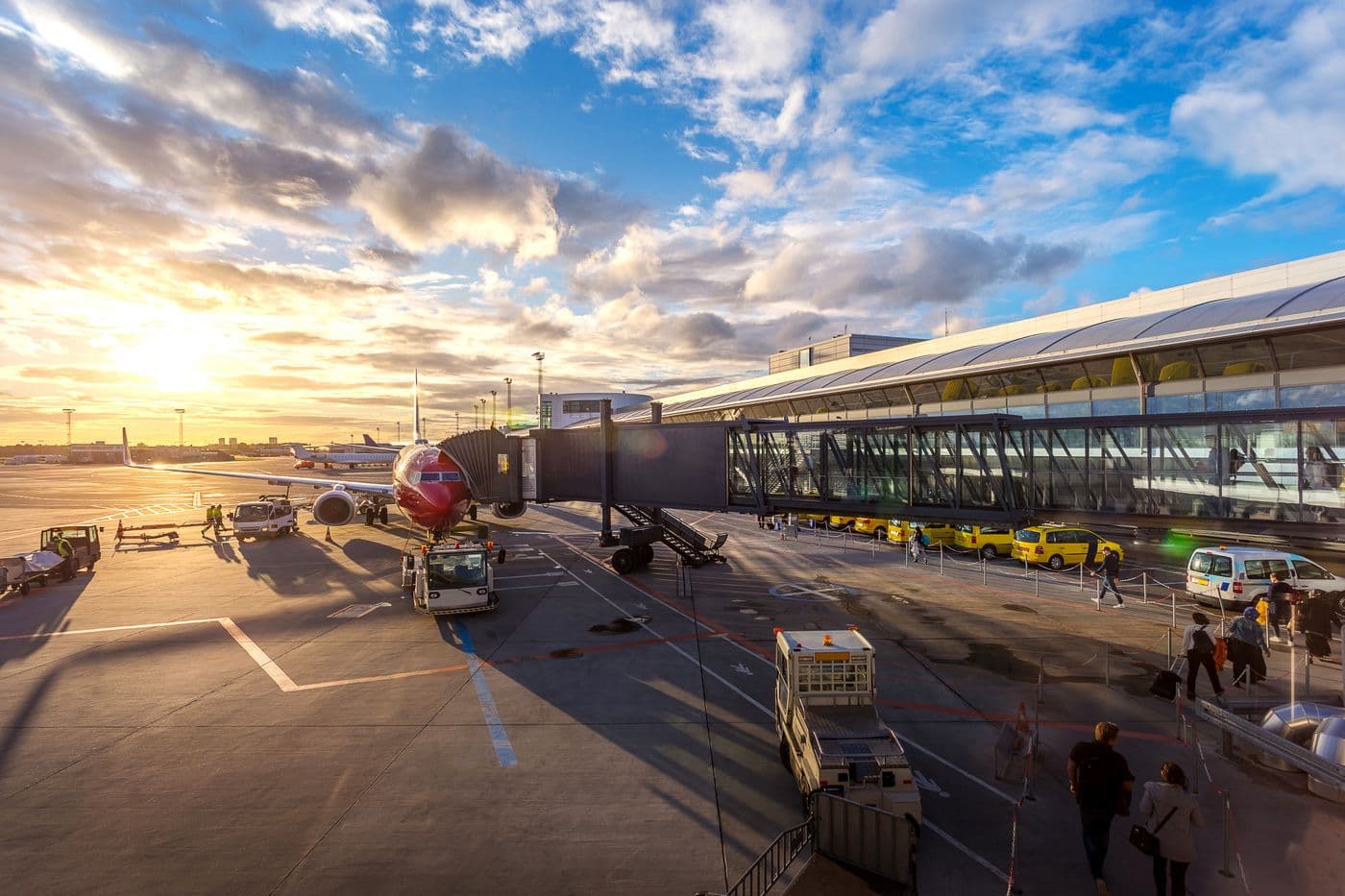 Yellow airport taxis waiting beside a parked aircraft at sunset